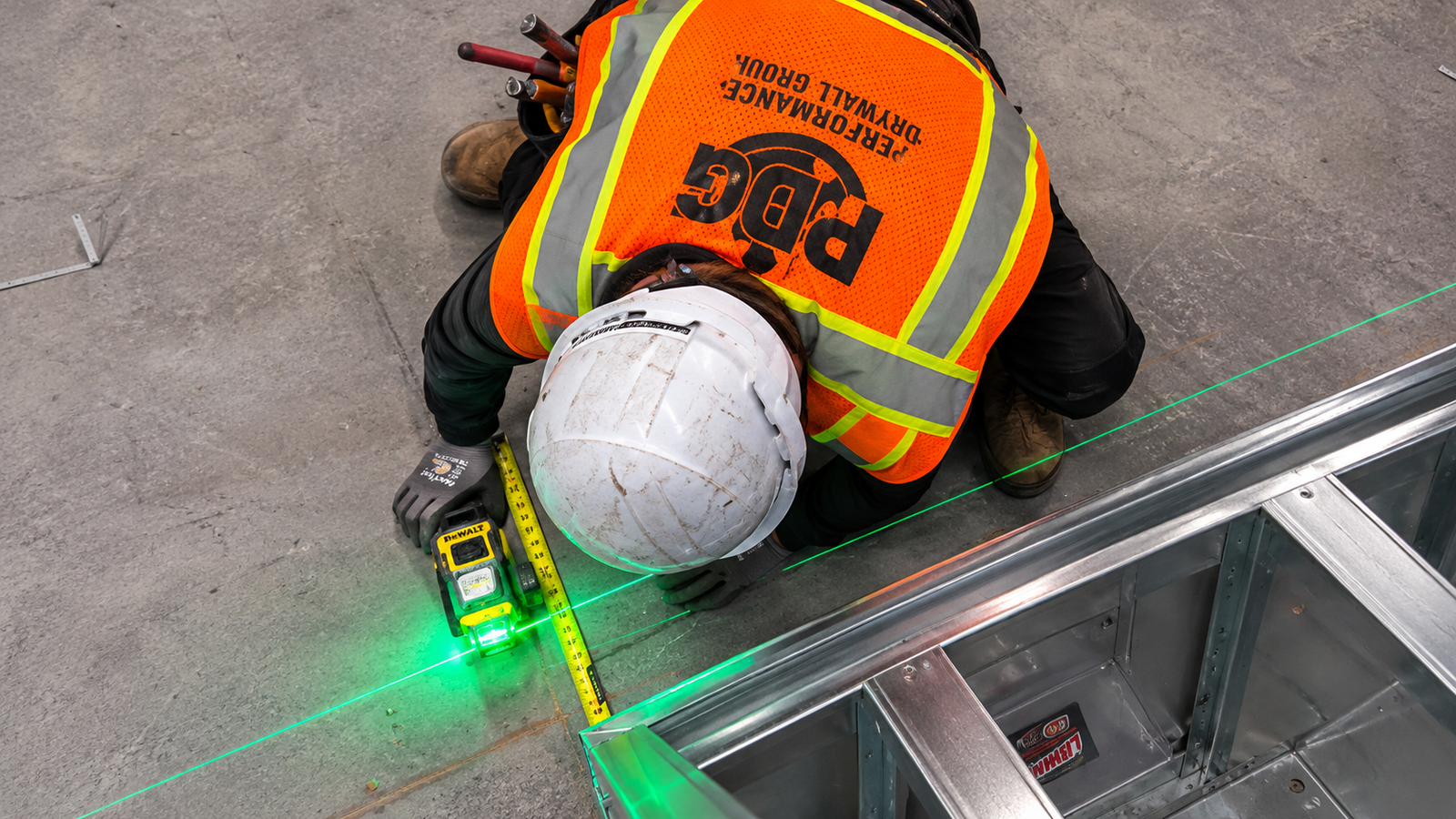 Worker using a laser level to lay out a metal framing installation